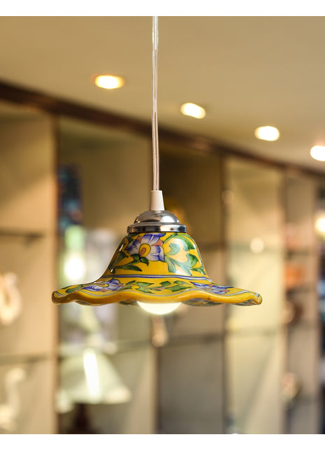 Colorful pendant light with a decorative glass shade against a blurred indoor background