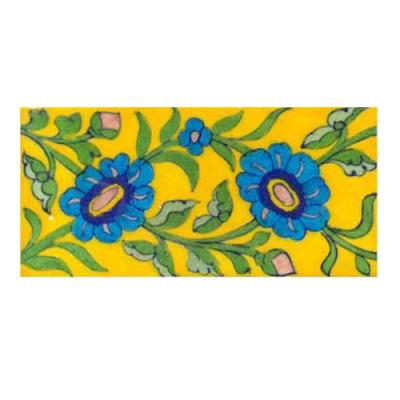 turquoise flower with green leaves on yellow tile